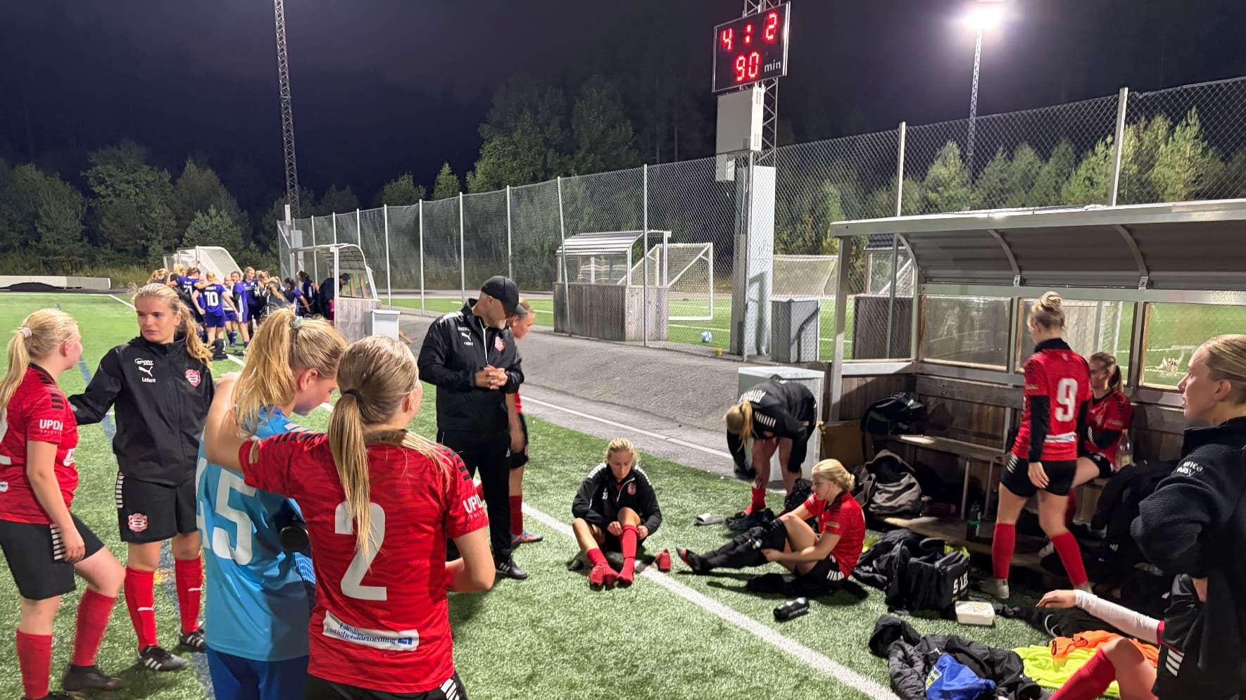 Runby IF women's team gathered by the team bench after a match in Upplands Väsby